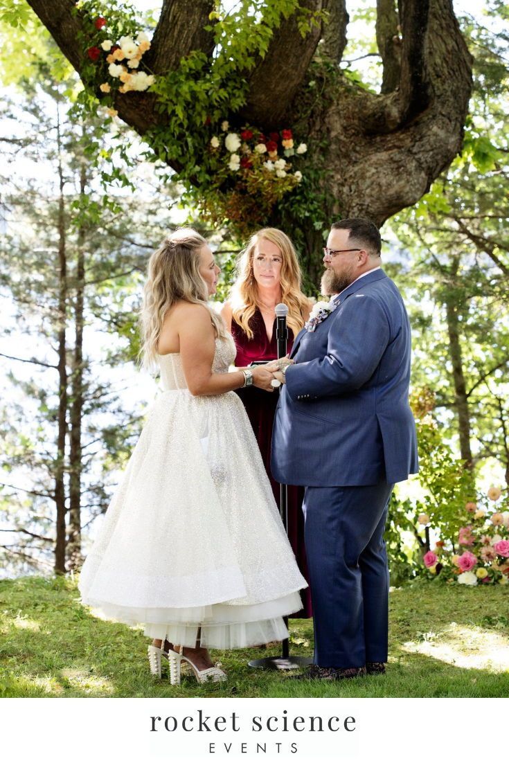 a man and woman standing under a tree during a wedding ceremony at the rockett science center