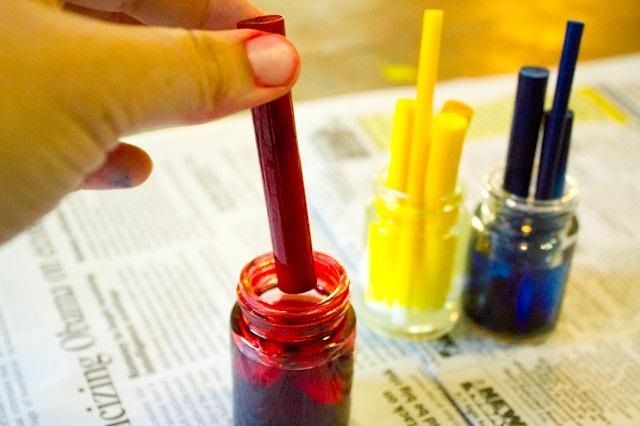 a person holding a pen in their hand next to three different colored pens on top of a newspaper