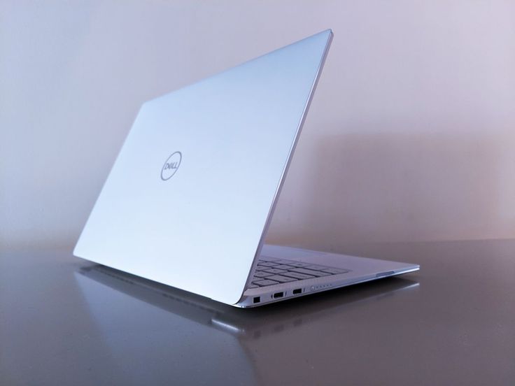 an open laptop computer sitting on top of a wooden table next to a white wall