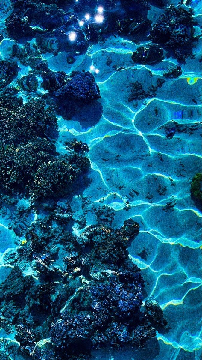 an underwater view of rocks and water with lights on them in the middle of the ocean