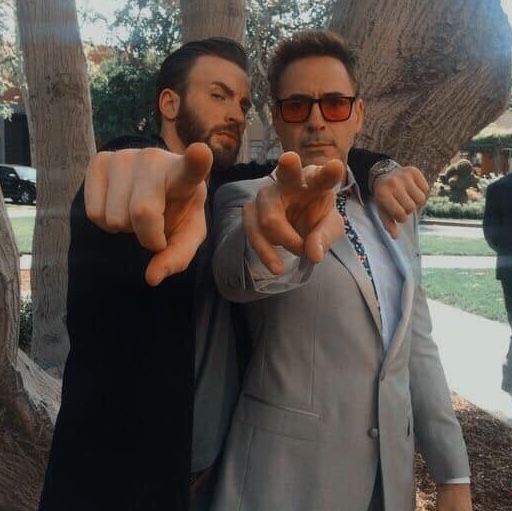 two men in suits and sunglasses pointing at the camera with their thumbs up while standing next to each other