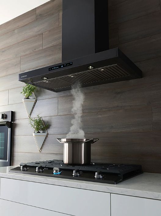 a stove top oven sitting inside of a kitchen next to a wall mounted pot filler