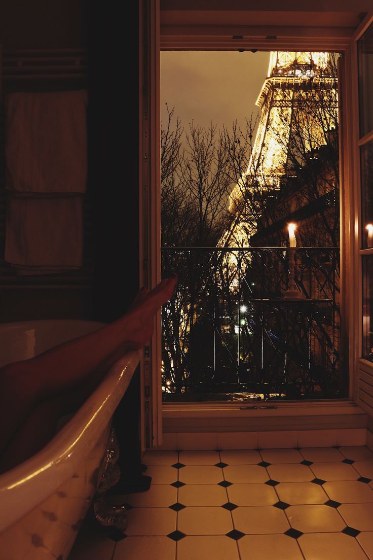 the eiffel tower is seen through an open window in a bathroom with black and white tile flooring