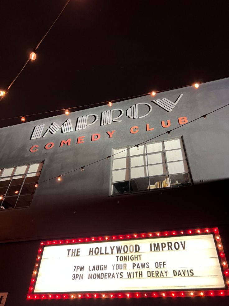 the hollywood imppov marquee is lit up at night with string lights