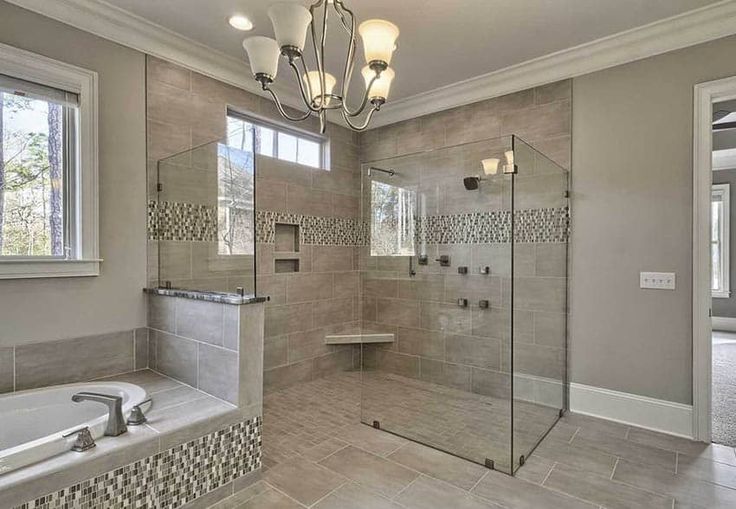 a bathroom with a walk in shower next to a bathtub and a sink under a chandelier