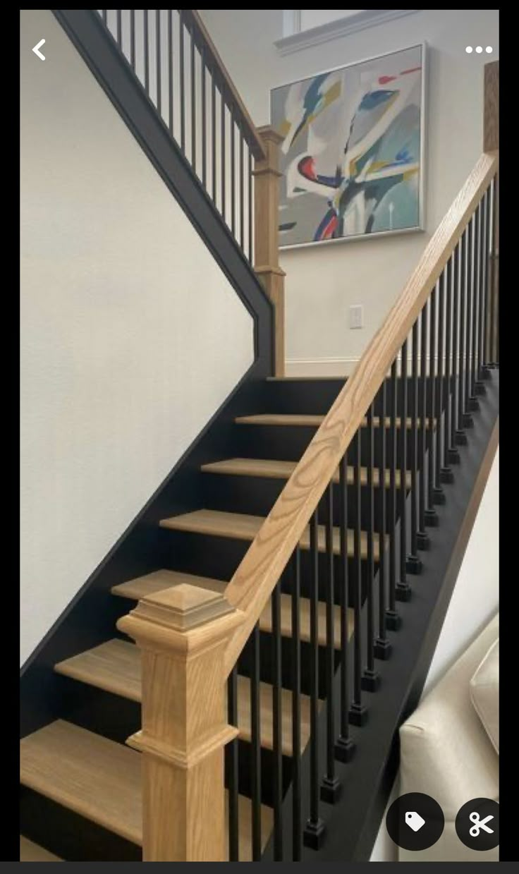 a staircase with black railing and wooden handrails