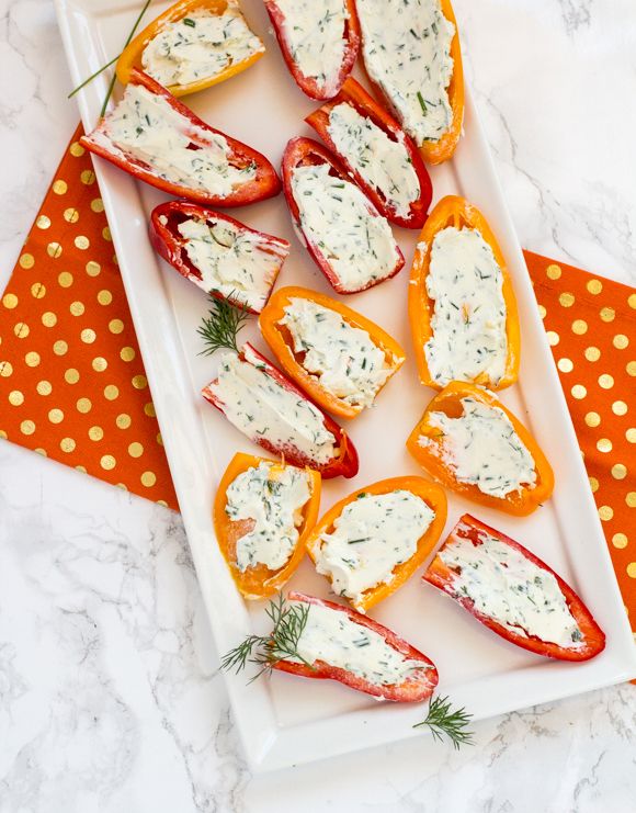 stuffed bell peppers with cheese and herbs on a white plate next to an orange napkin