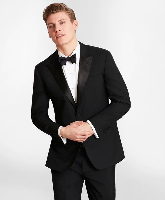 a young man in a tuxedo poses for the camera with his hands in his pockets