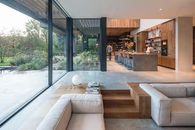 a living room with couches and tables in front of large glass windows that look out onto the backyard