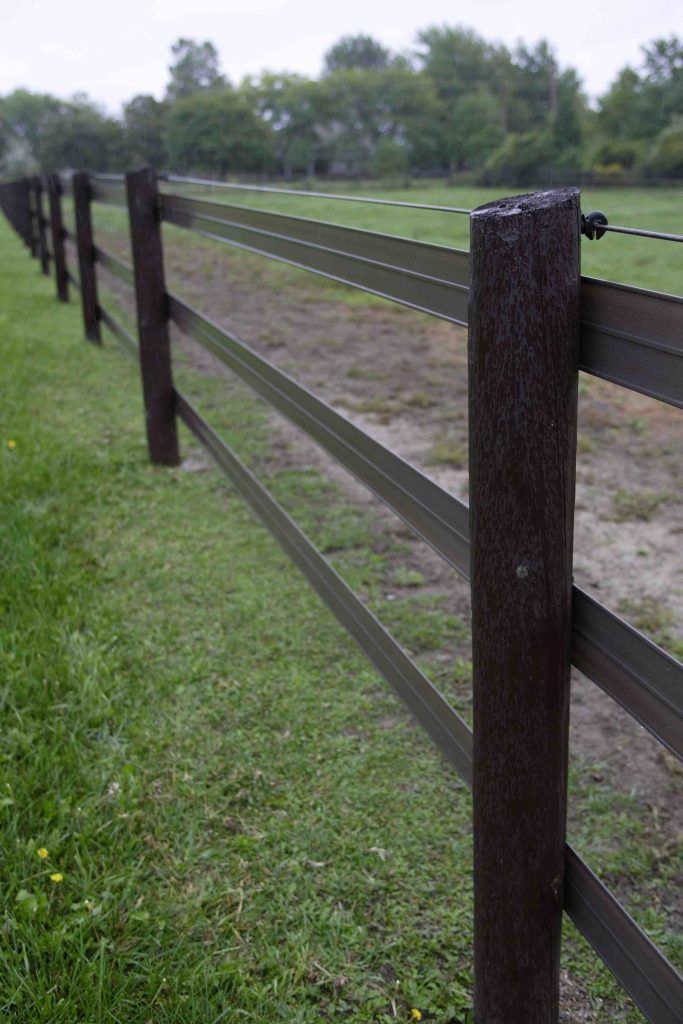 a wooden fence in the middle of a grassy field