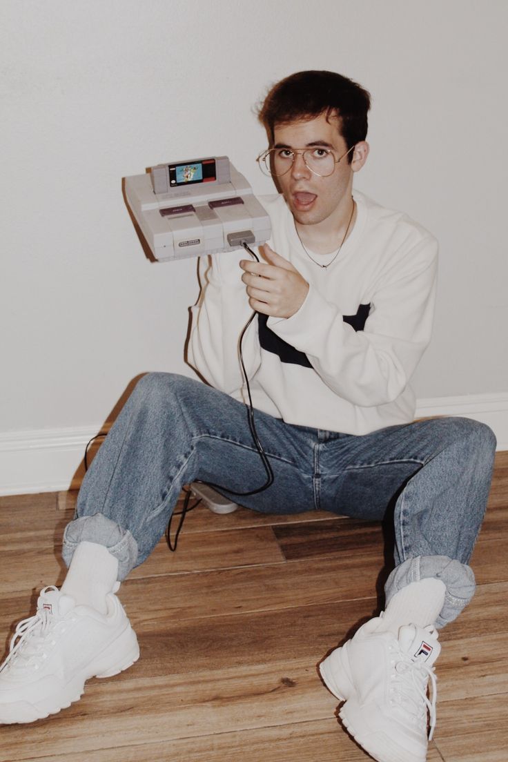 a man sitting on the floor holding an old video game controller in front of his face