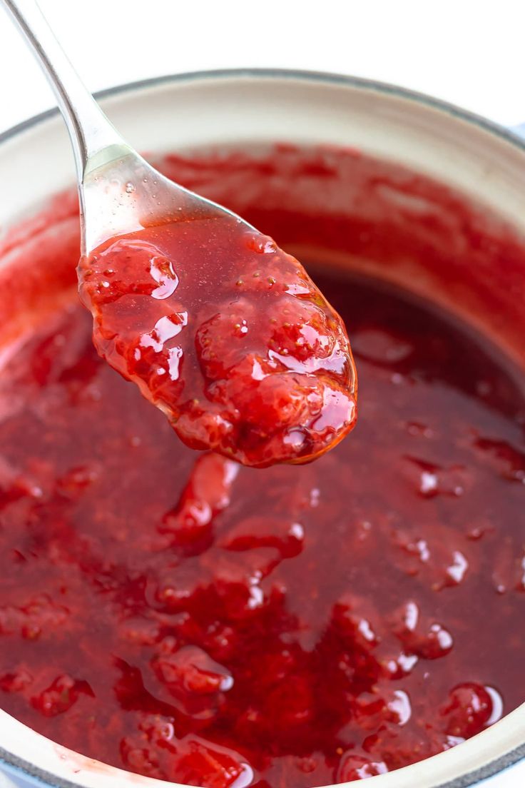 a spoon full of cranberry sauce on top of a pot