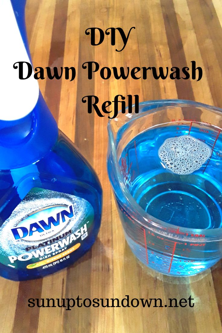 a bottle of dawn powerwash refill next to a bowl of water on a wooden table