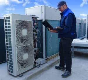 a man standing in front of two air conditioners looking at something on his tablet