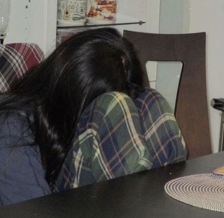 a woman sitting at a table with her head on the back of a chair