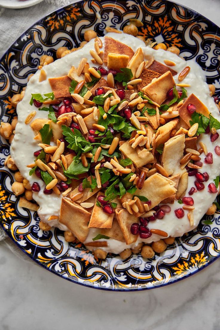 a blue and white bowl filled with food on top of a marble table next to utensils