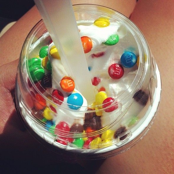 a person is holding a plastic cup filled with gummy bears and milkshakes