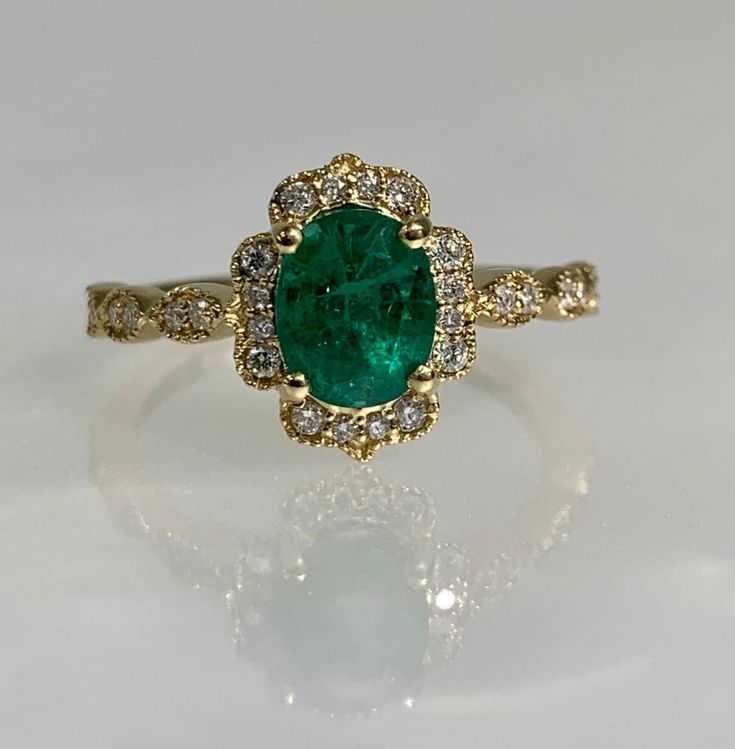 Oval Shaped ring, Oval shaped gold ring, Emerald ring, Emerald Engagement ring, Emerald Diamond ring, 14k gold ring, Oval Engagement ring A vibrant oval cut emerald ring featuring a 1.31-carat center stone accented by 0.20 carats of dazzling round brilliant cut diamonds set in solid 14k yellow gold. *Ring size: US 7 *Ring weight: 2.59 Grams *Center stone dimensions: 7.1X5.8mm Gold Oval Emerald Ring With Prong Setting, Exquisite Oval Ring With Halo Setting, Oval Yellow Gold Engraved Ring, Oval Engraved Yellow Gold Ring, Heirloom Oval Ring With Halo Setting, Exquisite Oval Rings With Halo Setting, Exquisite Oval Rings With Halo Design, Yellow Gold Halo Emerald Promise Ring, Oval Gemstone Engraved Ring For Wedding