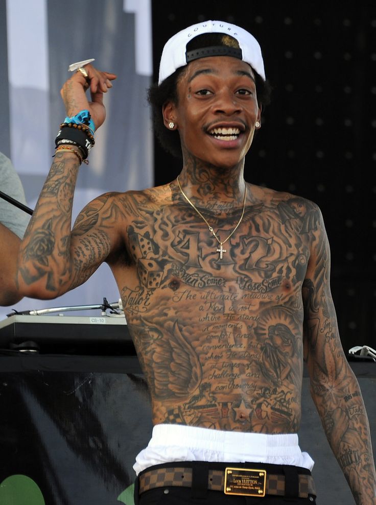 a man with many tattoos on his chest and arms, standing in front of a stage