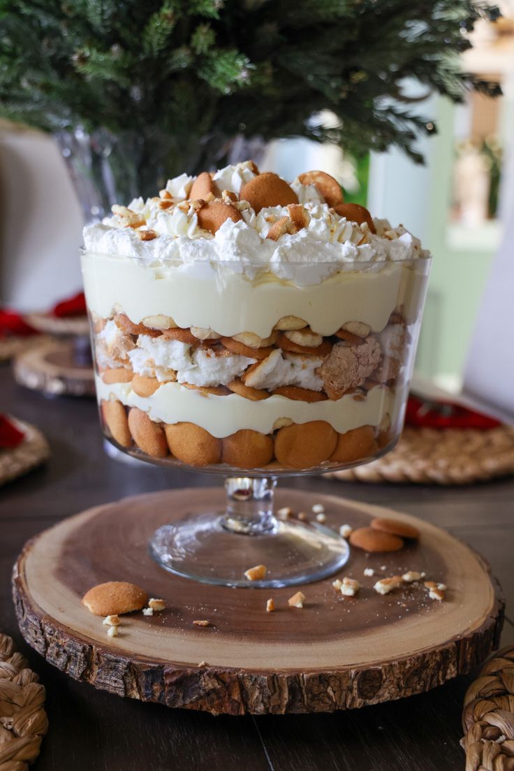 a layered dessert with nuts and cream in a glass dish on top of a wooden table