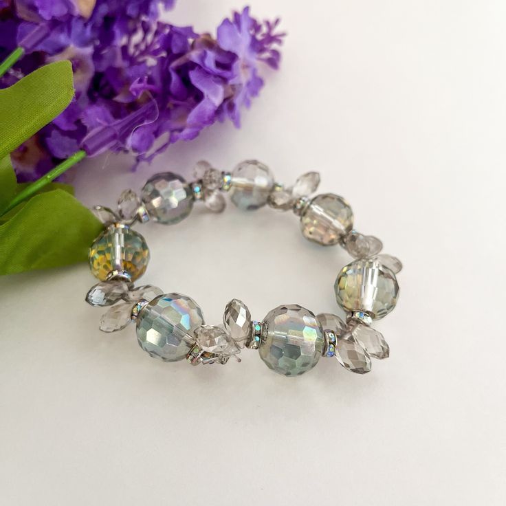 a close up of a bracelet with flowers in the background