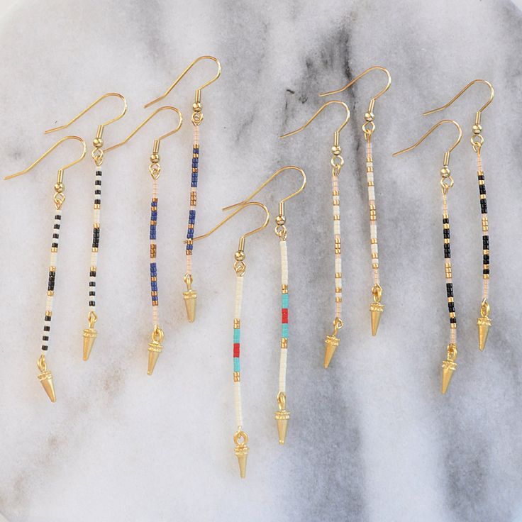 Edgy minimalism at its finest. These simple, long beaded stick earrings in a lean linear shape are just the right thing when you want a subtly cool accent. A tiny gold spike finishes the look with don't-mess-with-me edge. beaded gold-plated pin with tiny glass seed beads gold-plated stainless steel earwire hooks lead-free and nickel-free gold-plated spike charm plastic earring back 3 inches long packaged on a logo kraft card in a clear resealing bag Simple Bead Earrings, Long Beaded Earrings, Pebble Jewelry, Diy Earrings Easy, Homemade Bracelets, Stick Earrings, Beaded Earrings Diy, Plastic Earrings, Beading Techniques