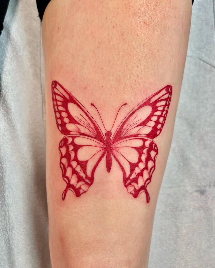 a red butterfly tattoo on the leg