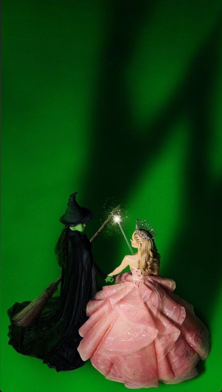 two figurines dressed in black and pink are standing next to each other on a green background