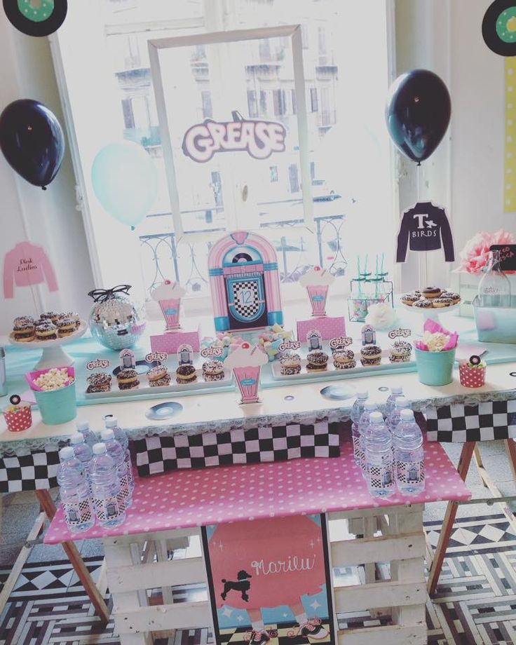 a pink table topped with lots of cupcakes and cakes