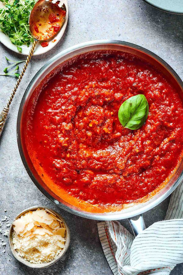 a pan filled with sauce and garnish on top of a table next to other dishes