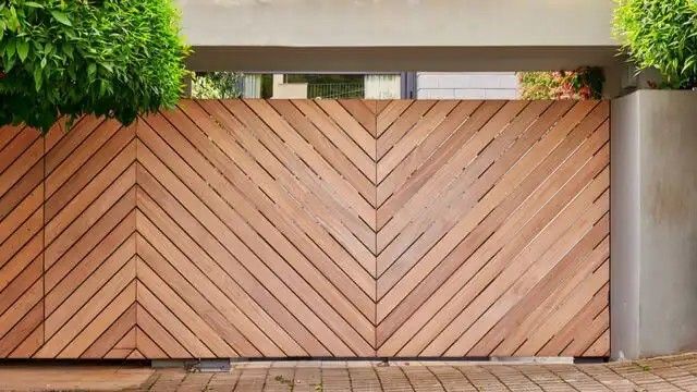 a wooden fence with plants growing on it's sides and an entrance to the house