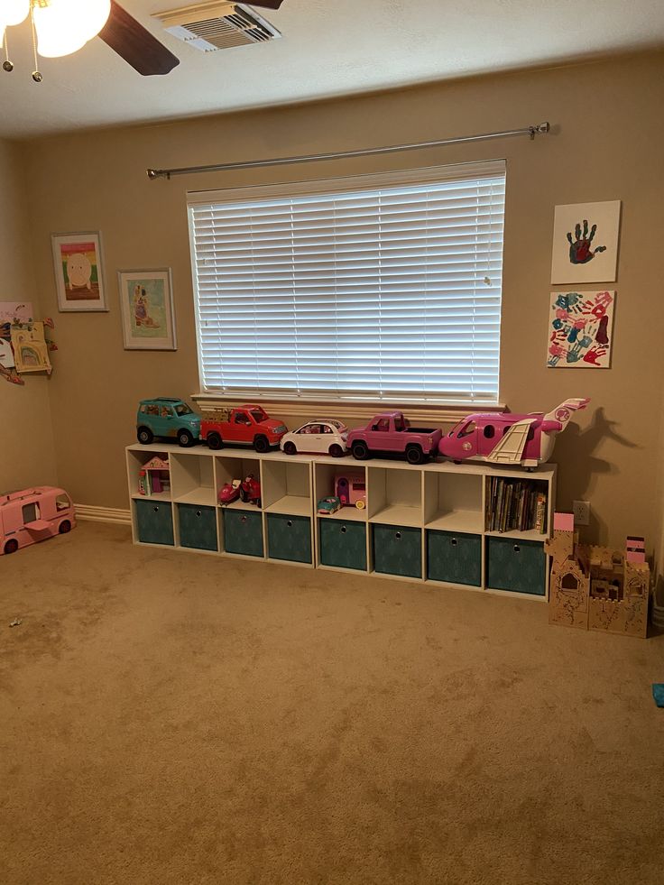 a child's playroom with toys on the floor and toy bins under the window