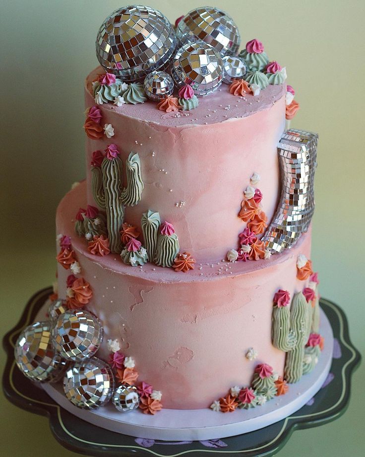 a three tiered cake decorated with cactus and disco balls