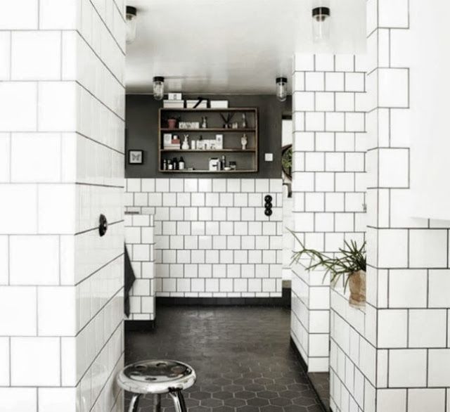 a white tiled bathroom with black and white floor tiles on the walls, along with a stool