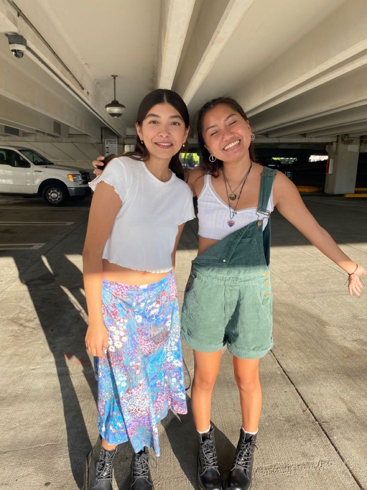 two young women standing next to each other in front of a parking garage with their arms around one another