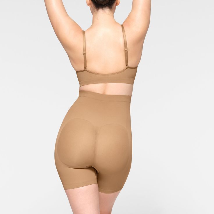 This mid waist short hits at the mid thigh and is the perfect solution for strong tummy and waist control with extra compression along the back thighs for a lifted look. Features large round butt pockets for a defined butt, an interior silicone underband to prevent rolling, and an open gusset. Fits true to size. | SKIMS Mid Thigh Short | Medium Neutral | Seamless Sculpt Sculpting Seamless Short-length Bottoms, Sculpting Seamless Mid-thigh Bottoms, Sculpting Seamless Mid-thigh Length Bottoms, Sculpting Smoothing Bottoms Mid-thigh Length, Sculpting Smoothing Mid-thigh Bottoms, Compressive Bottoms With Built-in Bra Mid-thigh Length, Seamless Shaping Shapewear In Elastane, Sculpting Shapewear With Contoured Waistband, Mid-thigh Length, Seamless Compression Shapewear, Mid-thigh Length