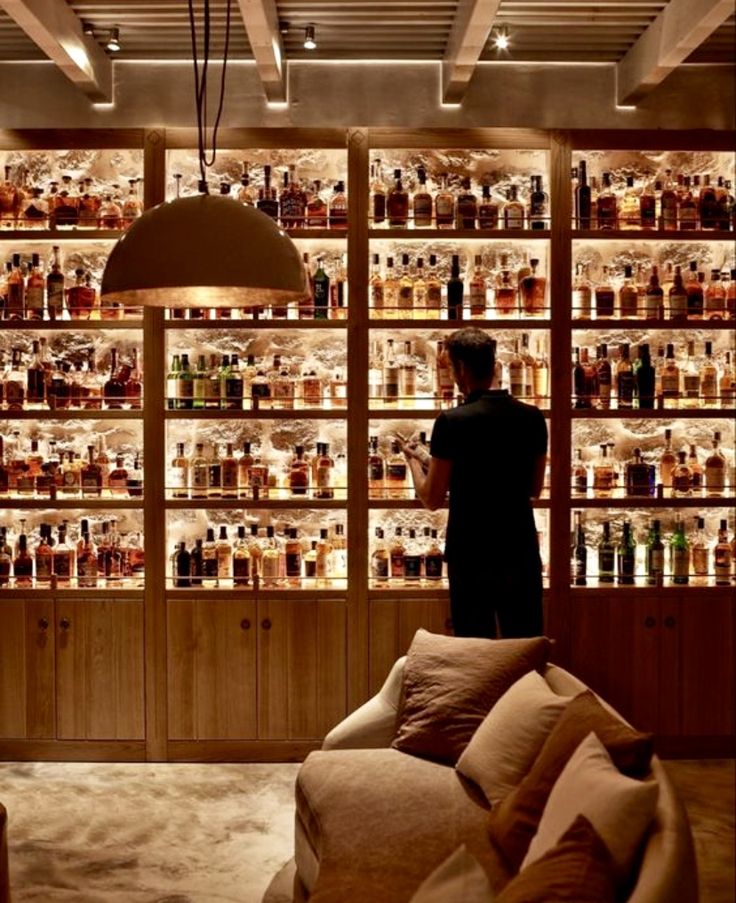 a man standing in front of a wall full of liquor bottles