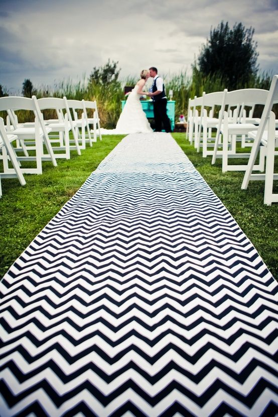 a bride and groom are standing at the end of an aisle with white chairs on it