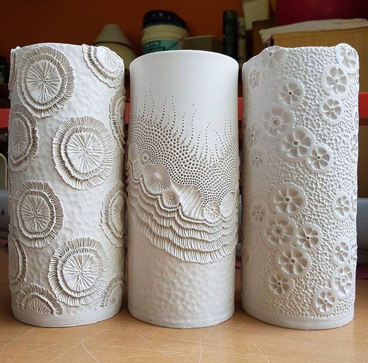 three white vases sitting on top of a wooden table