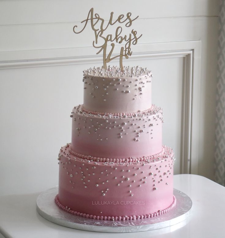 a three tiered cake with pink frosting and sparkles on top that says arles baby