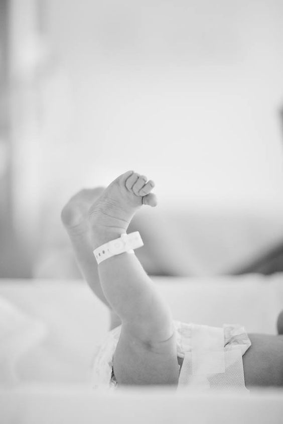 a black and white photo of a baby's arm with a bandage on it