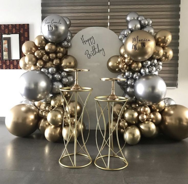 two gold and silver candlesticks with balloons in the shape of numbers on them