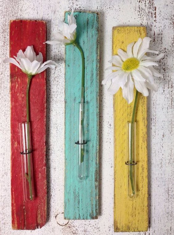 three wooden planks with flowers in them on the wall, one painted red, one yellow and one white