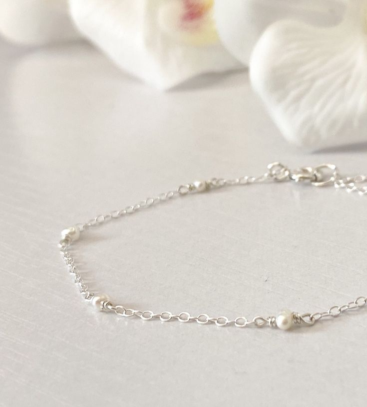 "This beautifully simple bracelet is lovingly handmade with a six tiny Freshwater Pearls and a choice of 14k Gold Filled, 14k Rose Gold Filled or Sterling Silver Chain. M A T E R I A L S: * Freshwater Pearl * 14k Gold Filled, 14k Rose Gold Filled or Sterling Silver Chain S I Z E: *  Gemstones - Approximately 2-3mm *  Chain Thickness - Approximately 1.1mm  All of our jewellery is carefully handmade using good quality materials and handpicked gemstones, with the aim to produce quality pieces that you can love & wear for years to come.  P E A R L: * June Birthstone * Talisman for Gemini, Cancer * Third Eye Chakra Pearl signifies faith, charity and innocence.  It enhances personal integrity and helps to provide a focus to ones attention.  Pearl symbolises purity and is known as a \"stone of si Minimalist Single Strand Beaded Bracelets As Gift, Minimalist Single Strand Beaded Bracelets For Gift, Dainty Sterling Silver Pearl Bracelet, Minimalist Sterling Silver Pearl Bracelet, Everyday Delicate Sterling Silver Pearl Bracelet, Adjustable Delicate Sterling Silver Bracelet As A Gift, Minimalist Adjustable Pearl Bracelet For Anniversary, Minimalist Sterling Silver Pearl Bracelet For Wedding, Minimalist Sterling Silver Bracelets For Bridesmaids