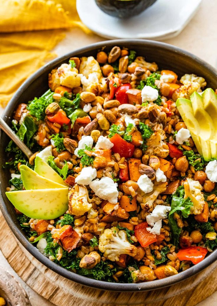 a bowl filled with vegetables and nuts on top of a wooden table