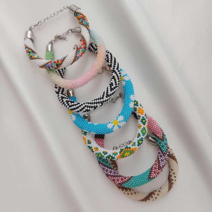 a bunch of bracelets that are sitting on a white surface with beads and chains around them