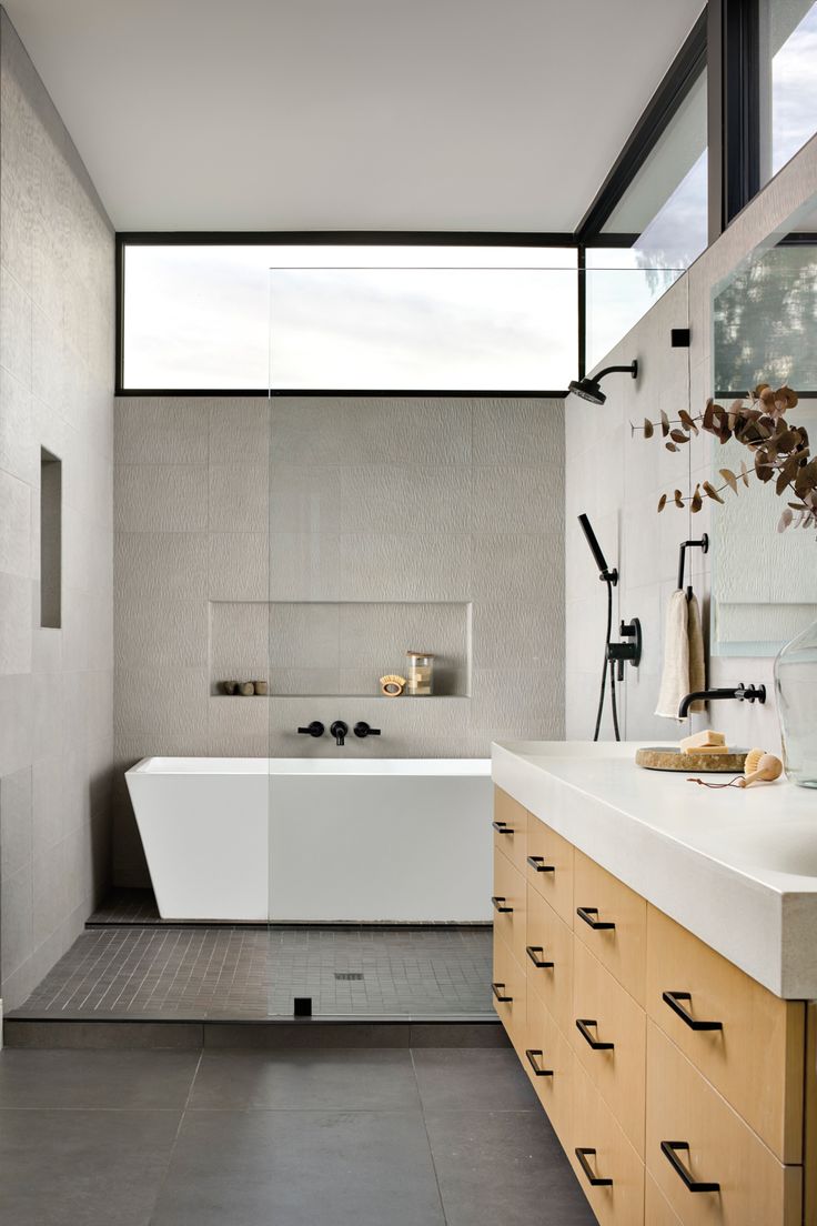 a bathroom with a large white bath tub sitting next to a sink and a window