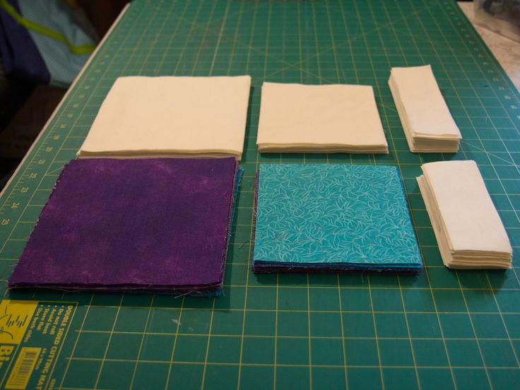 four pieces of paper are laid out on a cutting board and ready to be cut into squares