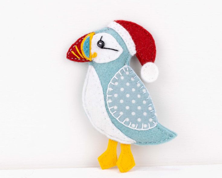 a stuffed bird with a santa hat on it's head is standing against a white wall