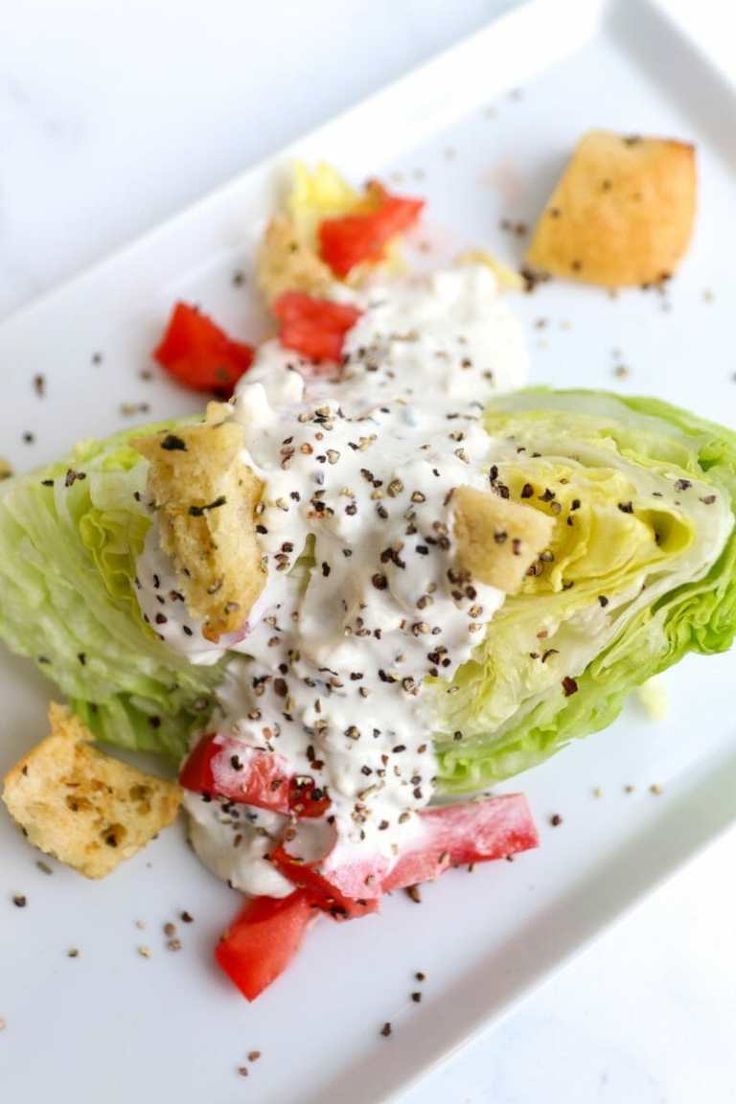 a white plate topped with lettuce covered in ranch dressing